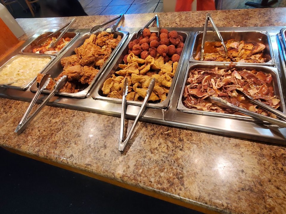 Buffet counter with hot trays and serving utensils.